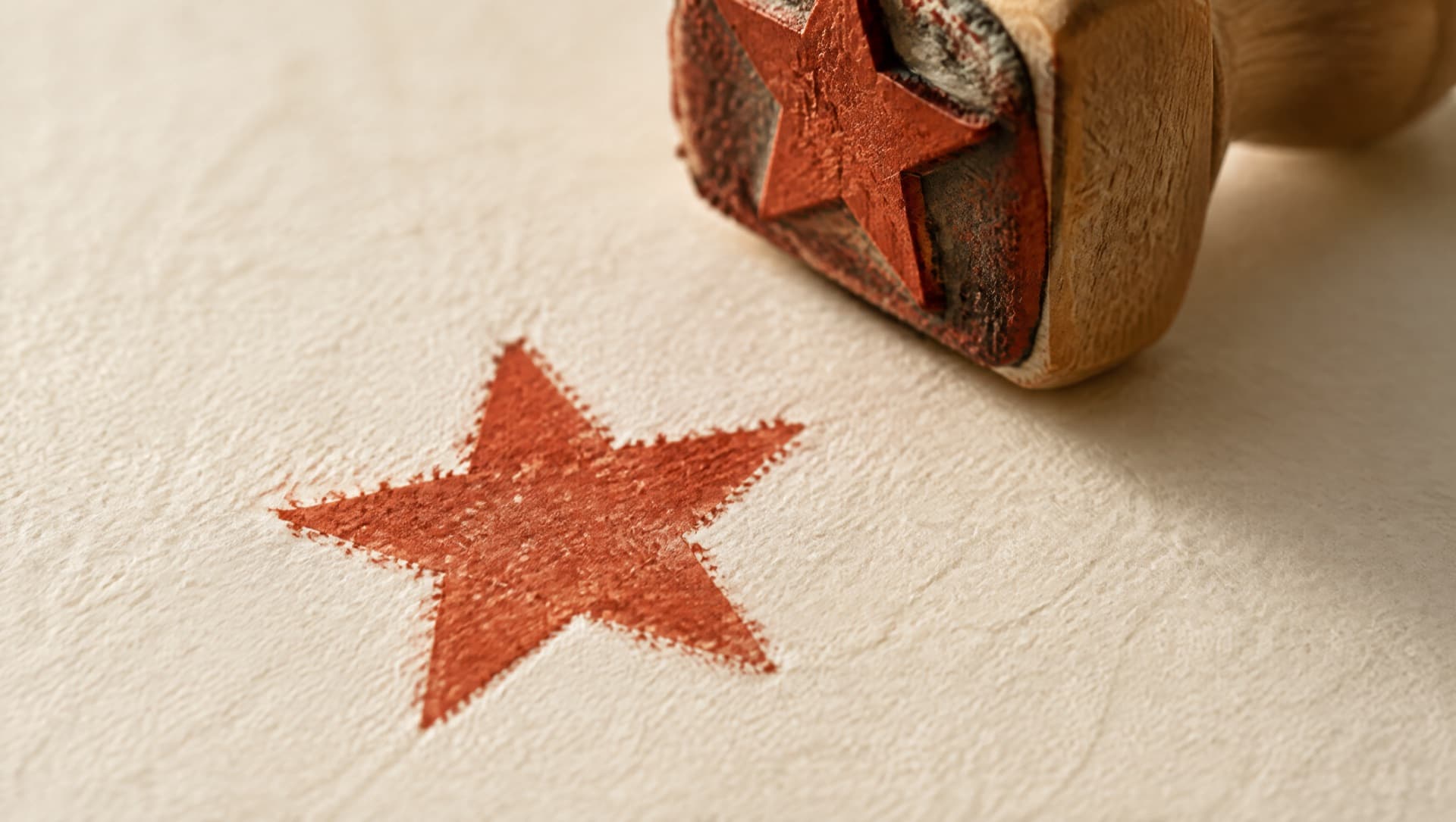 Un sello de hule recién levantado del papel deja impresa una estrella en tinta terracota.